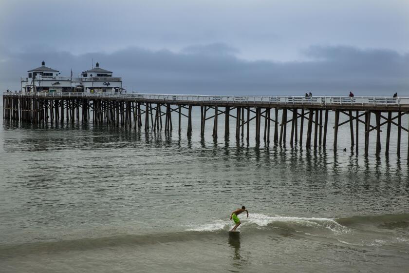 Christian Rodriguez, 19, of Santa Barbara skimboards at the Malibu Pier with low clouds in the background on Thursday, June 11, 2015 in Malibu, California. Forecasters say chance for strong El Nino increased to more than 90%.