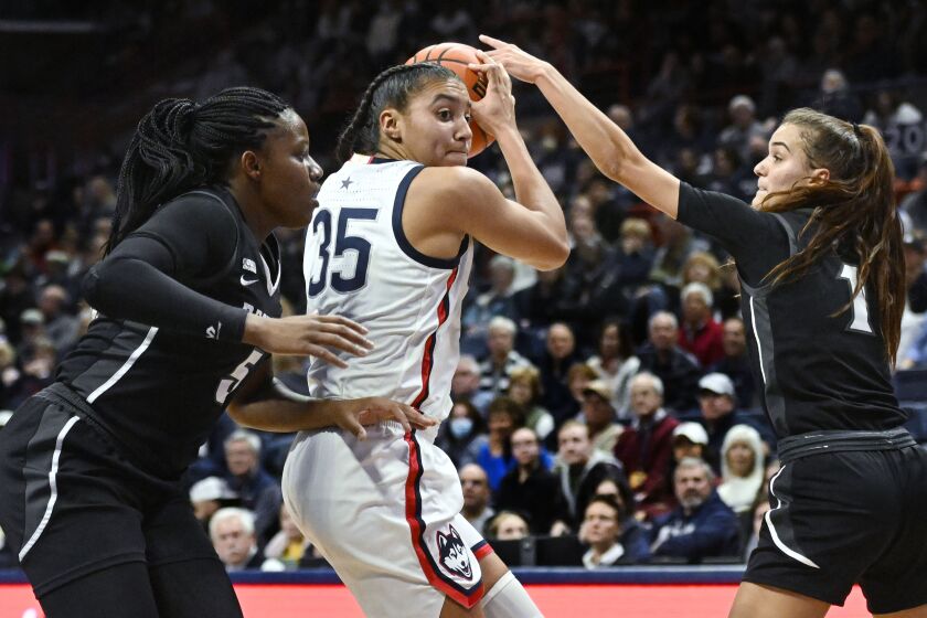 Connecticut's Azzi Fudd (35) is pressured by Providence's Janai Crooms, left, and Kylee Sheppard, right, in the first half of an NCAA college basketball game, Friday, Dec. 2, 2022, in Storrs, Conn. (AP Photo/Jessica Hill)