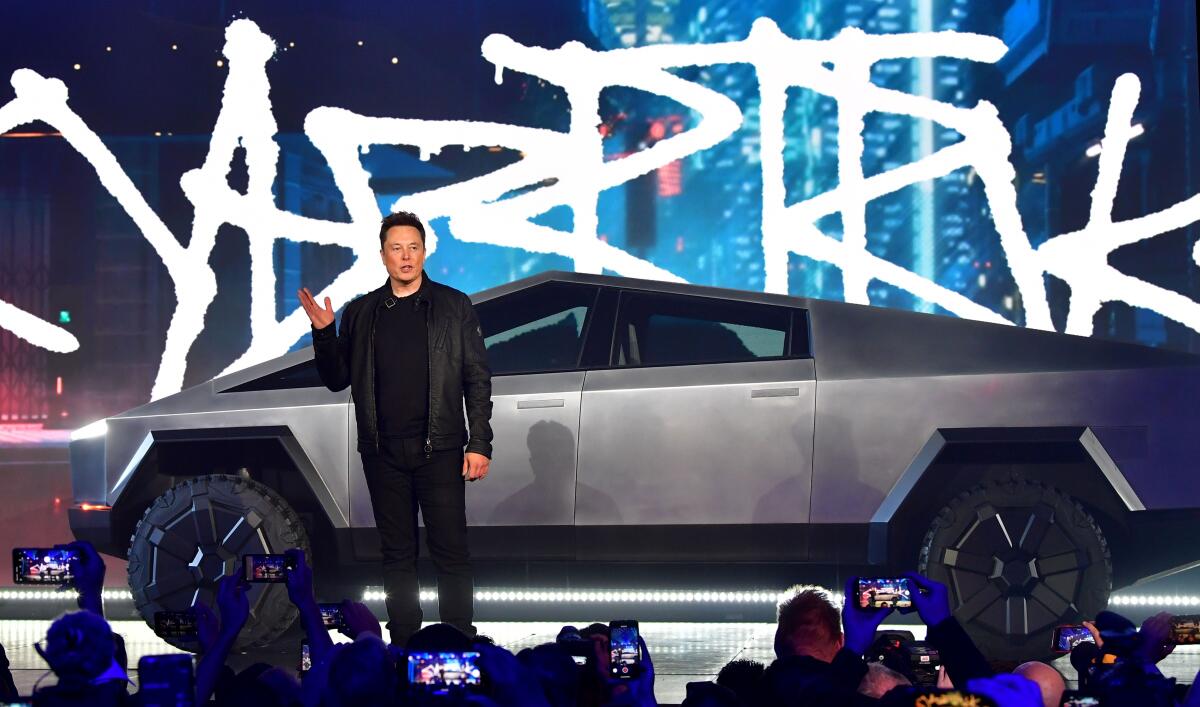 Elon Musk stands in front of a Cybertruck 
