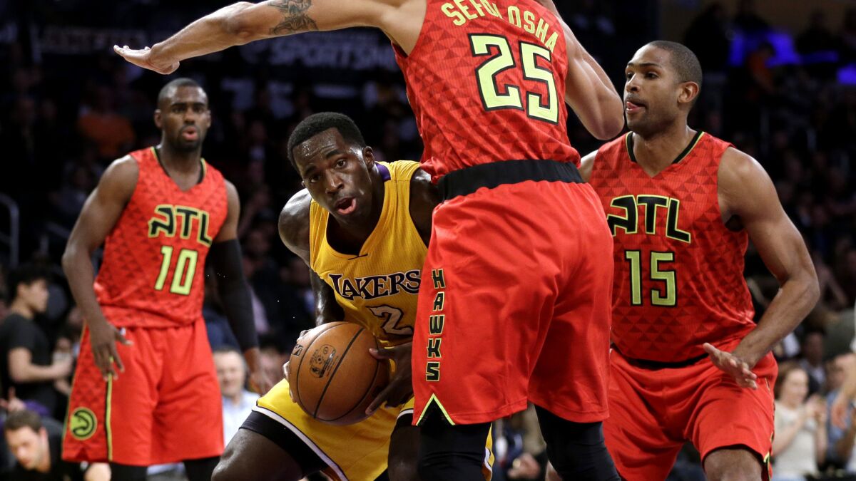 Lakers forward Brandon Bass looks to score inside against Hawks guard Thabo Sefolosha (25) and center Al Horford (15) during the first half,