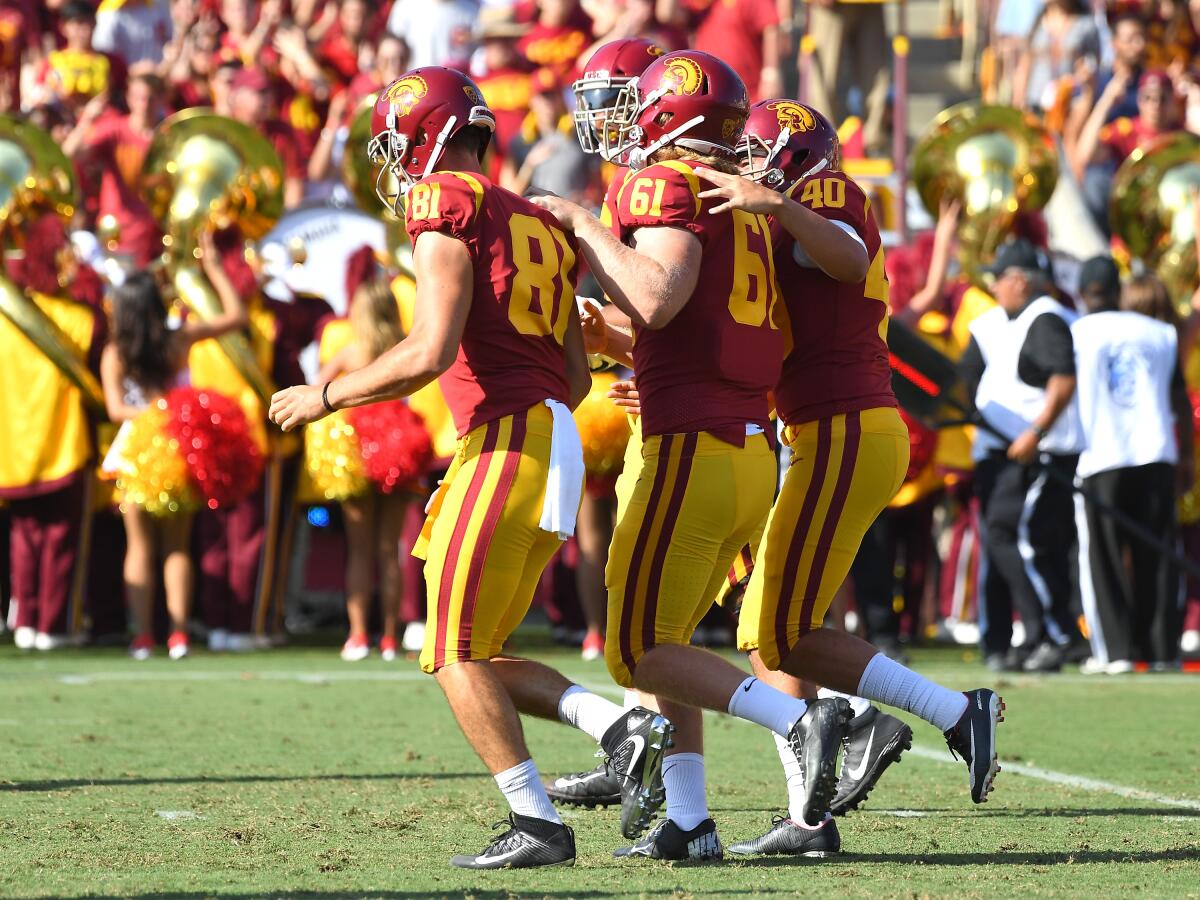 USC's blind long snapper, Jake Olson (61), is escorted off the field by teammates after he snapped the ball.