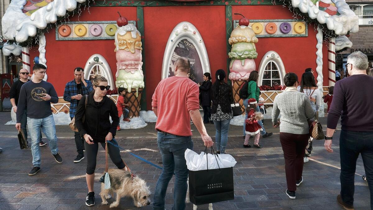 Holiday shoppers walk past Santa's Workshop for some last-minute gifts at the Grove.