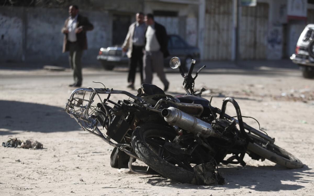 Palestinians walk near the debris of a damaged motorcycle after an Israeli airstrike in Deir al-Balah, central Gaza Strip, Sunday.