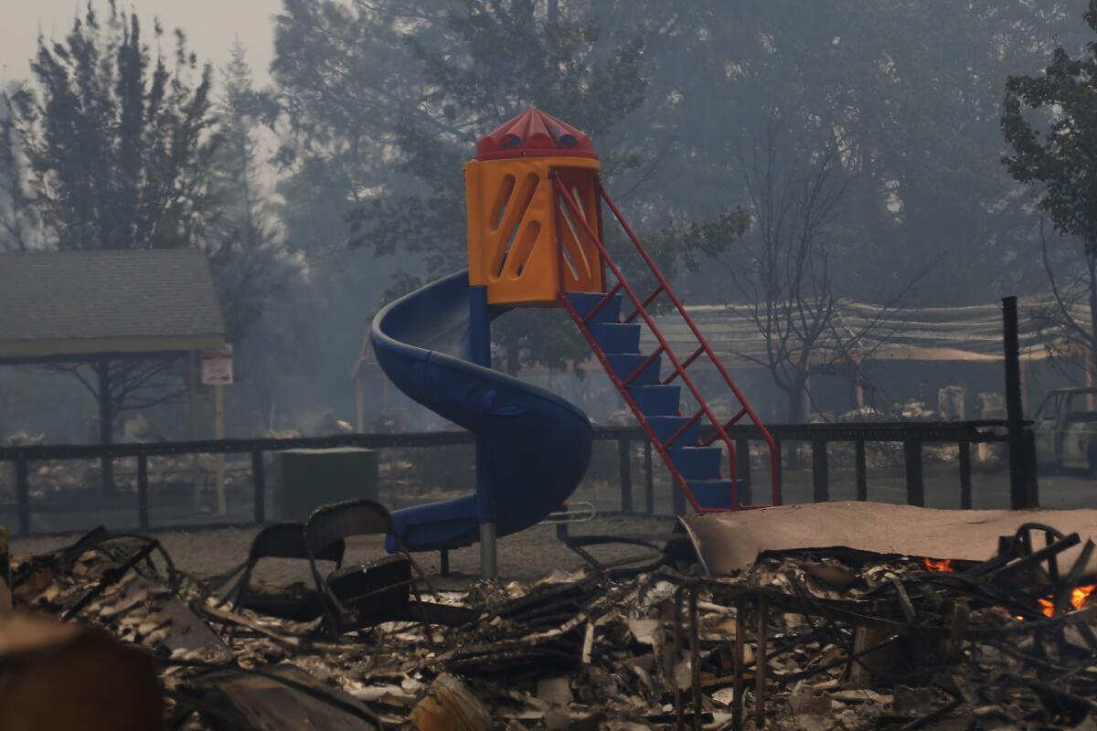 A playground slide stands among smoldering rubble of the Valley fire in Middletown, Calif.