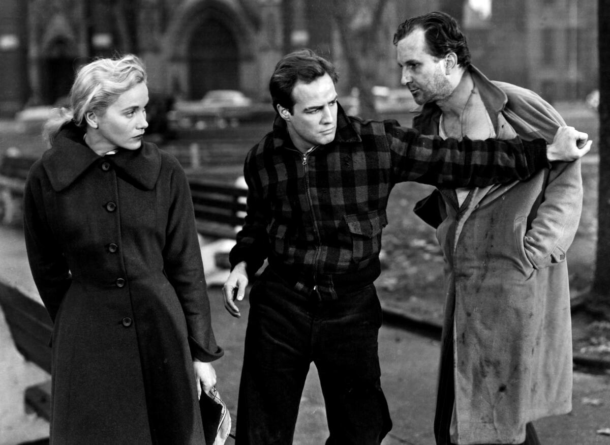 Eva Marie Saint watches as Marlon Brando pushes away a man in “On The Waterfront” (1954)
