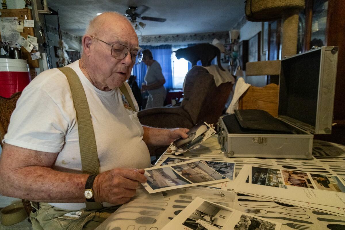 Chris Christensen, 86, looks at photos.