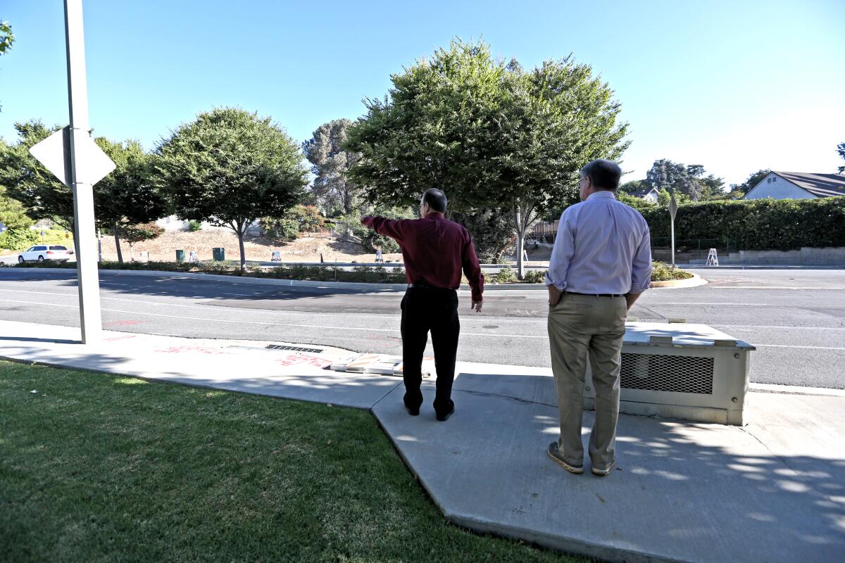 La Canada Flintridge Public Works Director Pat DeChellis, left, and Lutheran Church of the Foothills member David Haxton talk Tuesday morning near the area where a large dip in the road has developed, on 1700 block of Foothill Boulevard.