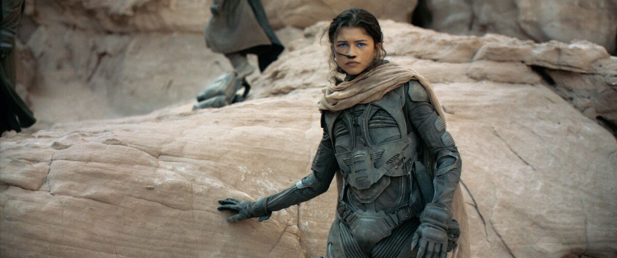 Zendaya wears a futuristic costume in a desert landscape in a scene from "Dune."