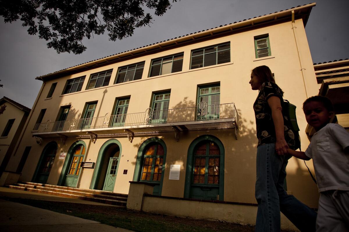 A women and a child walk by the long-shuttered YWCA in Pasadena.