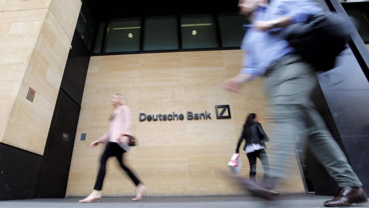 People walk past Deutsche Bank's London offices on Monday. The German company is cutting as many as 18,000 jobs.