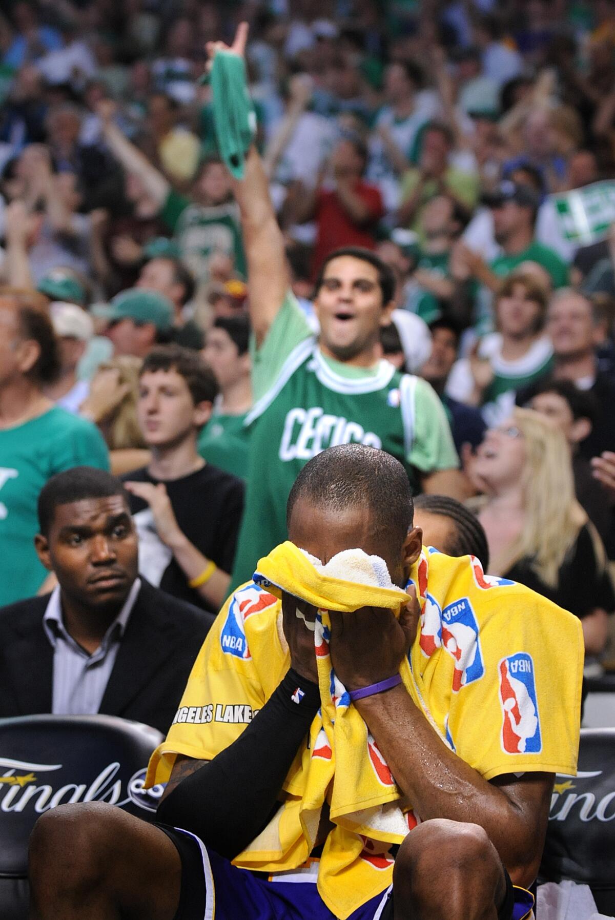 Celtics fans celebrate a playoff win as Kobe Bryant puts his head in a towel 