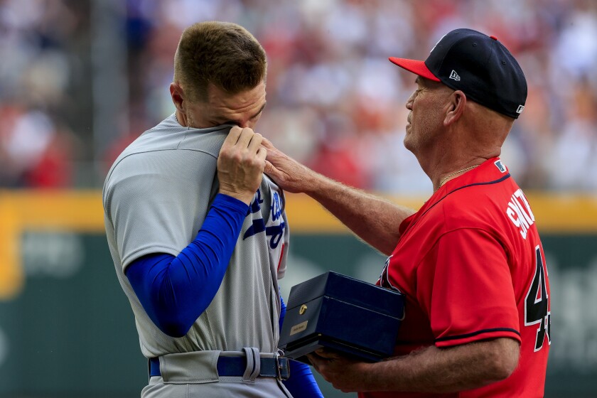 Los Angeles Dodgers first baseman Freddie Freeman, left, reacts as he is presented his World Series championship ring by Atlanta Braves manager Brian Snitker before a baseball game Friday, June 24, 2022m in Atlanta. (AP Photo/Butch Dill)