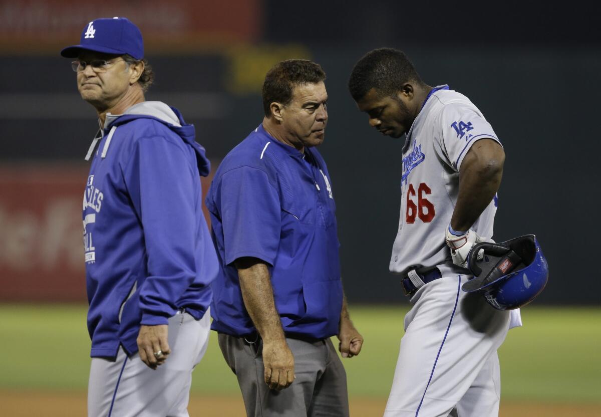 Yasiel Puig speaks with trainer Stan Conte in the eighth inning against Oakland on Tuesday night.