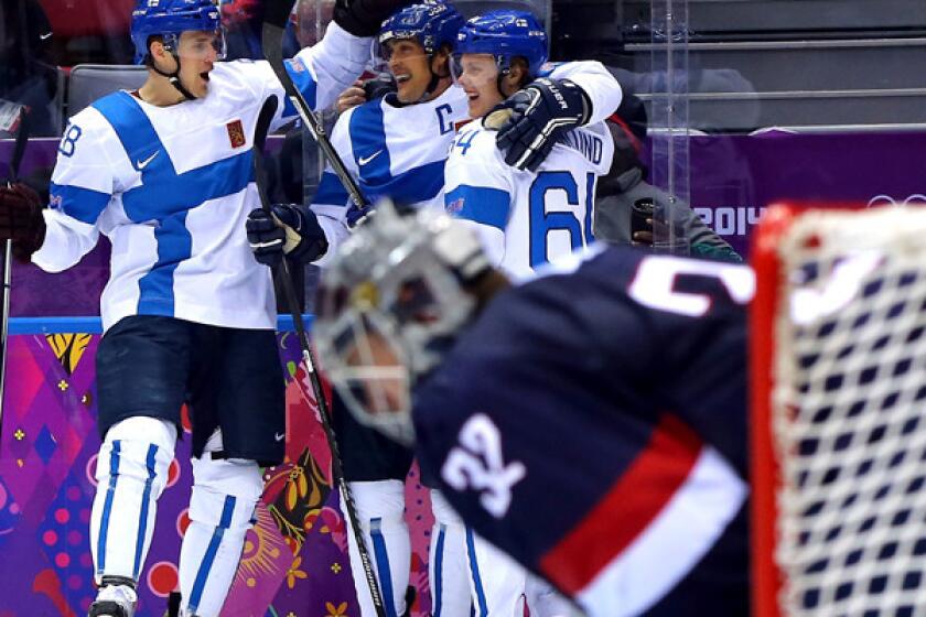 Finland captain Teemu Selanne, center, is congratulated by teammates Lauri Korpikoski (28) and Mikael Granlund (64) after scoring against goalie Jonathan Quick (32, foreground) and the United States in the second period of the bronze medal game on Saturday at the Sochi Olympics.
