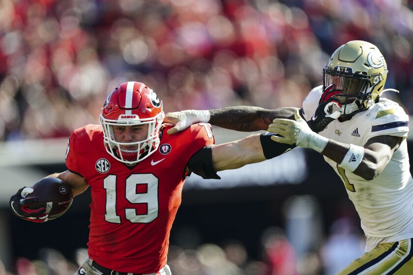 Georgia tight end Brock Bowers (19) fends off Georgia Tech defensive back Zamari Walton (7) as he run after a catch during the first half of an NCAA college football game Saturday, Nov. 26, 2022 in Athens, Ga. Bowers was called for a face masking penalty. (AP Photo/John Bazemore)