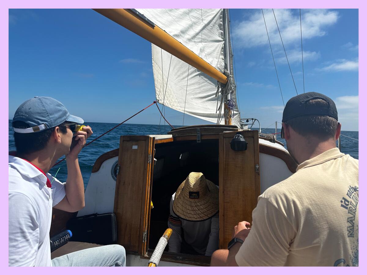 Three men on a sailboat with blue sky in the background