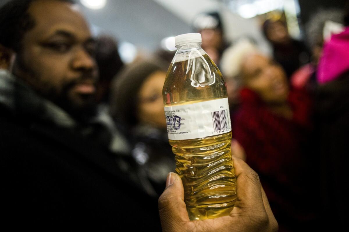 A protester holds up a bottle of yellow tap water from Flint, Mich., at a demonstration. 