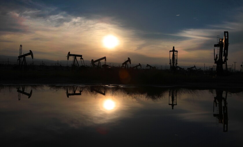 Oil pumps and equipment are reflected in a pool of water at the South Belridge oil field in Kern County.