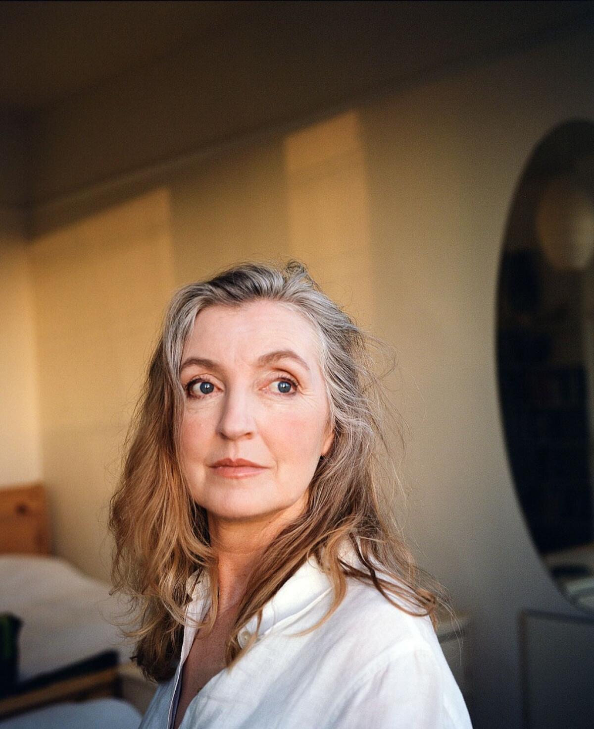 A woman with gray hair looks over her left shoulder 