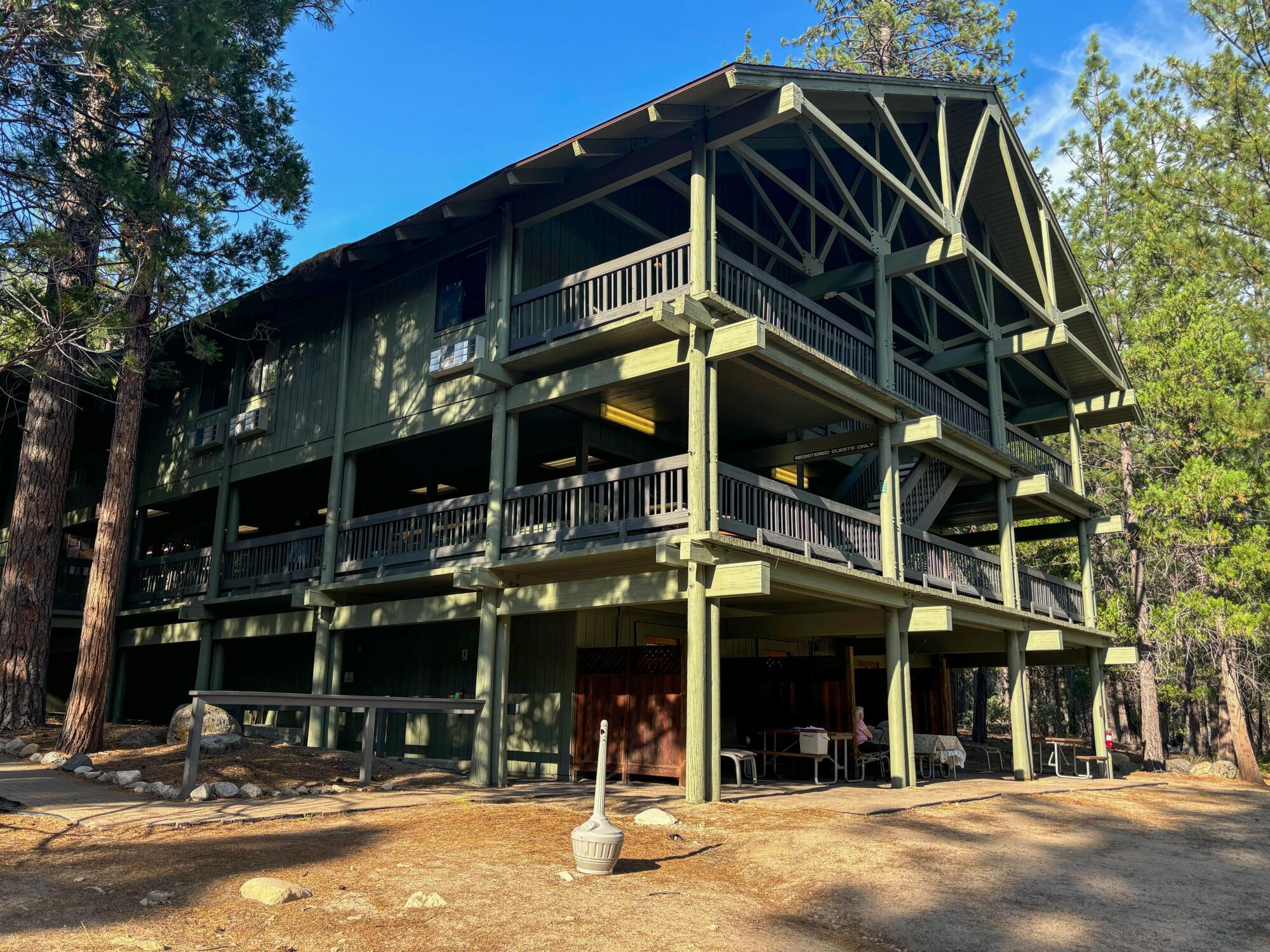 A three-story wooden green hotel in a forest