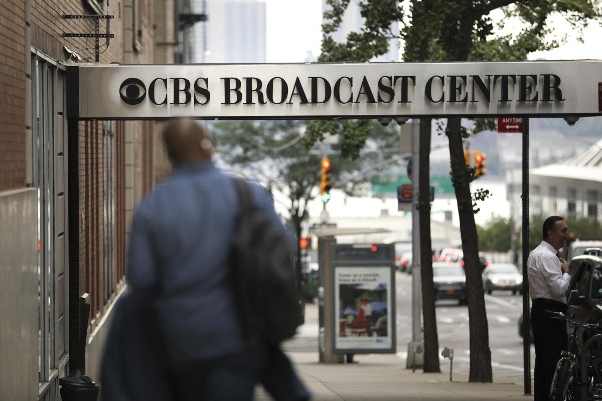 A man walks under the entryway sign for CBS Broadcast Center in New York City 