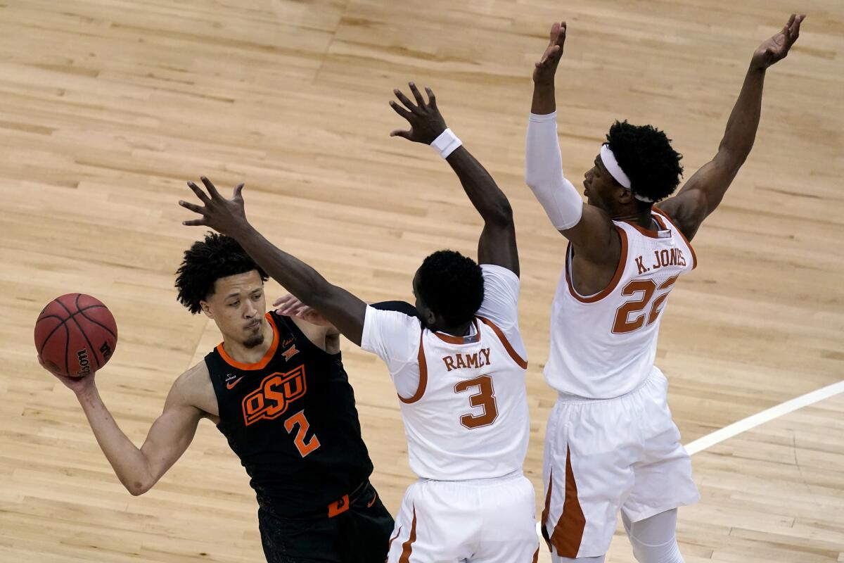Oklahoma State's Cade Cunningham looks to pass under pressure from Texas's Kai Jones (22) and Courtney Ramey (3) during the first half of an NCAA college basketball game for the Big 12 tournament championship in Kansas City, Mo, Saturday, March 13, 2021. (AP Photo/Charlie Riedel)