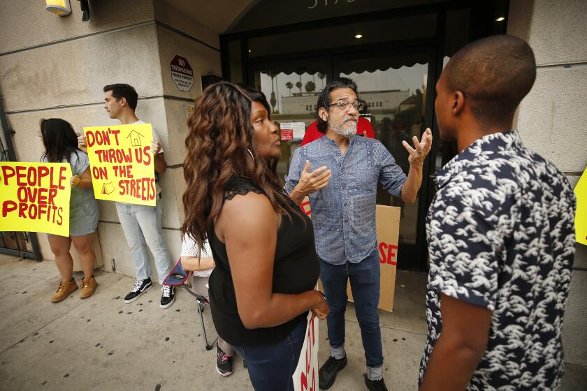 LOS ANGELES, CA - JULY 31, 2019 Rene Alexander, center, of the Hillside Villa Tenants Association and the L.A. Tenants Union talks to Carla Miller, left, and Charlie Peppers, right, residents of the Kingswood Apartments as fellow residents of the apartments located at 5173 Hollywood Blvd in East Hollywood held a news conference to discuss their concerns regarding a rent increase of more than 20 percent on July 31, 2019. (Al Seib / Los Angeles Times)
