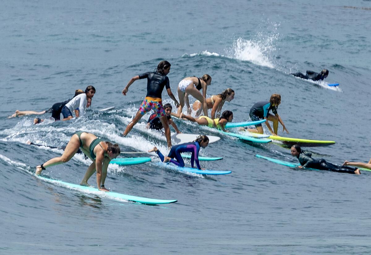 A crowd of surfers attempt to ride a wave together 