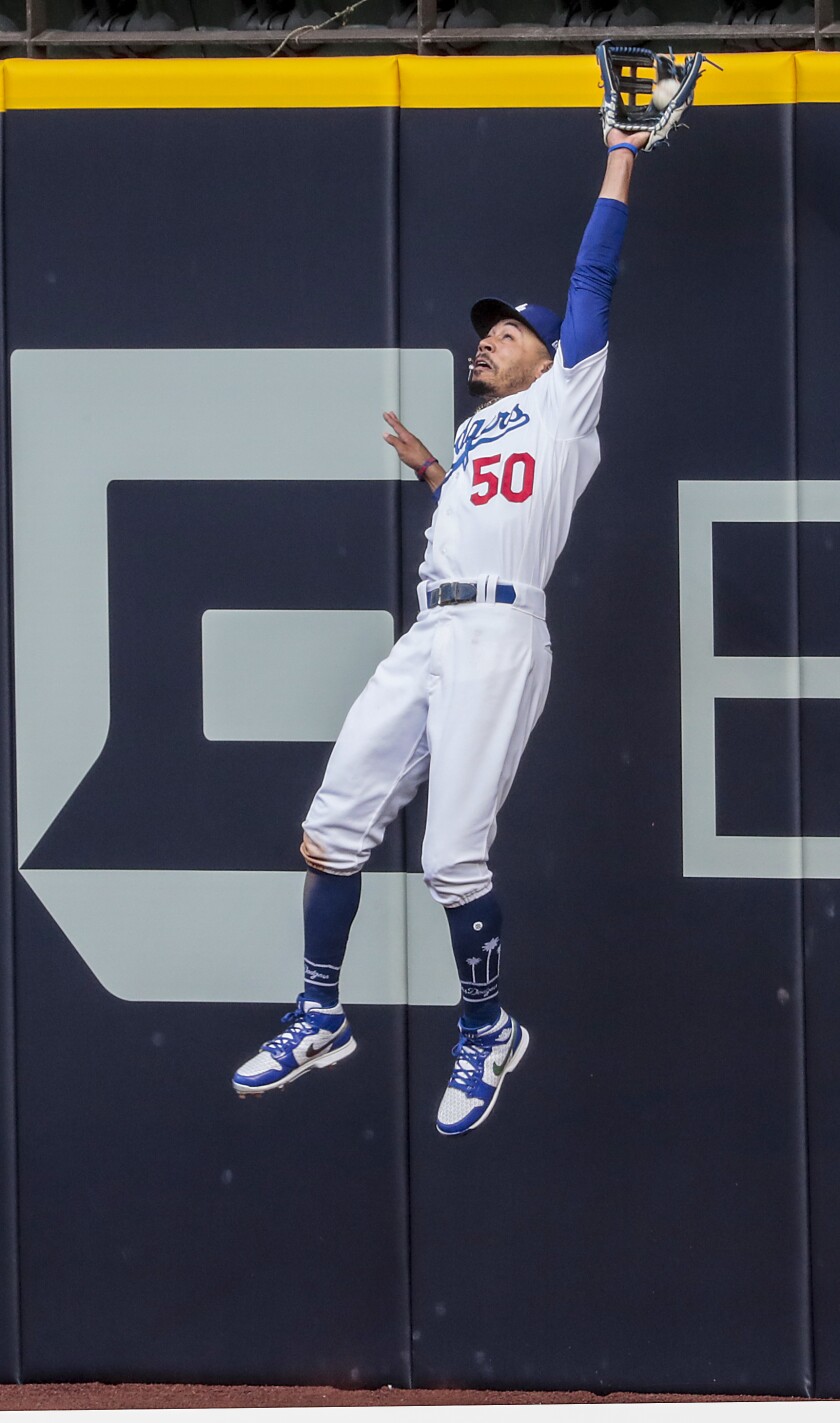 Dodgers right fielder Mookie Betts leaps to catch a ball hit by Braves designated hitter Marcell Ozuna.