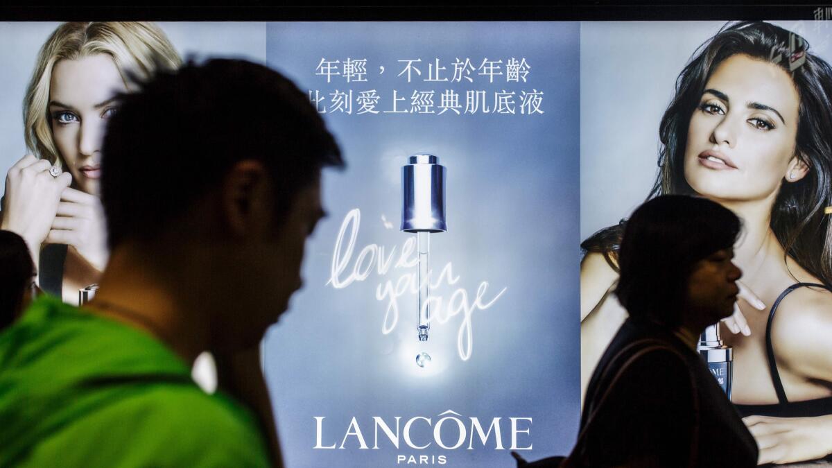 Commuters walk past a Lancome ad in Hong Kong on June 6, 2016. People urged a boycott of the luxury brand after it canceled a concert featuring a pro-democracy singer.