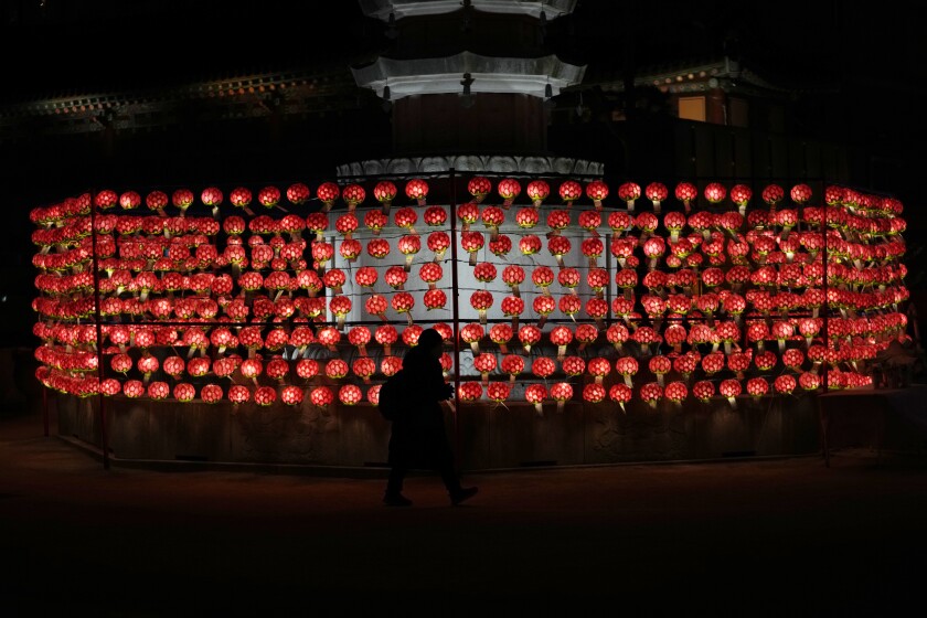 A woman prays in front of lanterns on New Year's Eve at the Jogye temple in Seoul, South Korea, Friday, Dec. 31, 2021. (AP Photo/Lee Jin-man)