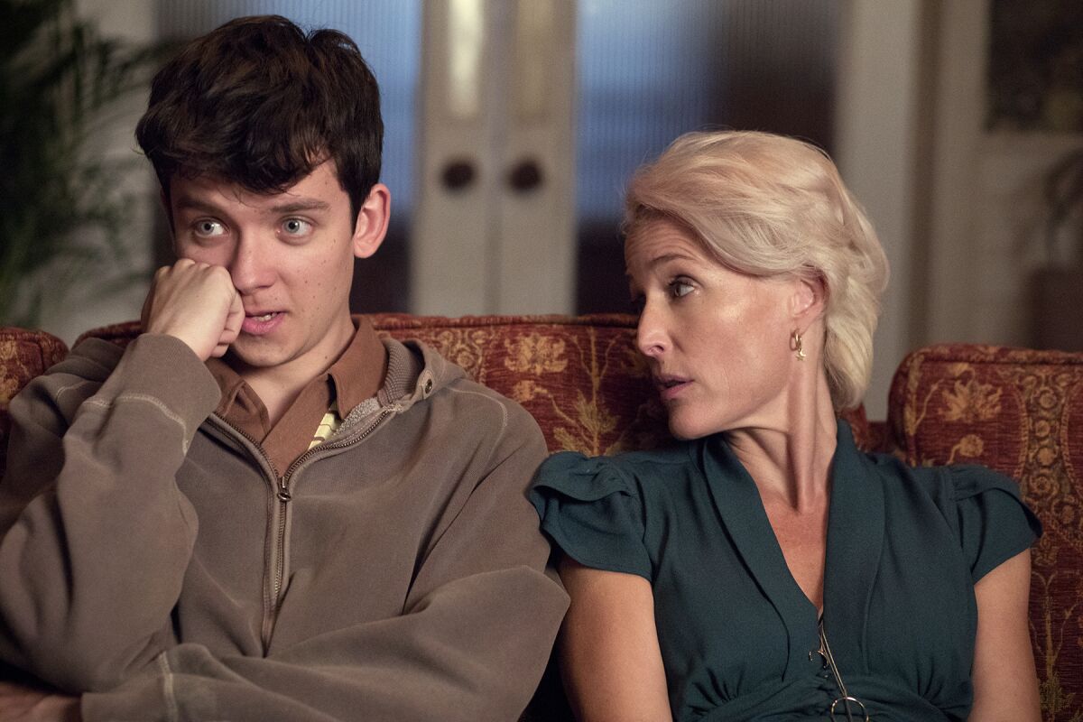 A man and a woman sit side by side on a couch.