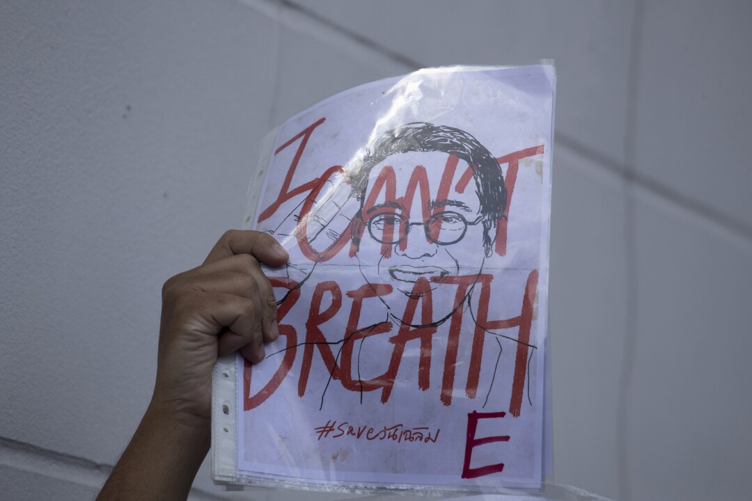 Un attivista tiene in mano una foto di Wanchalearm Satsaksit durante una manifestazione davanti all'ambasciata cambogiana a Bangkok