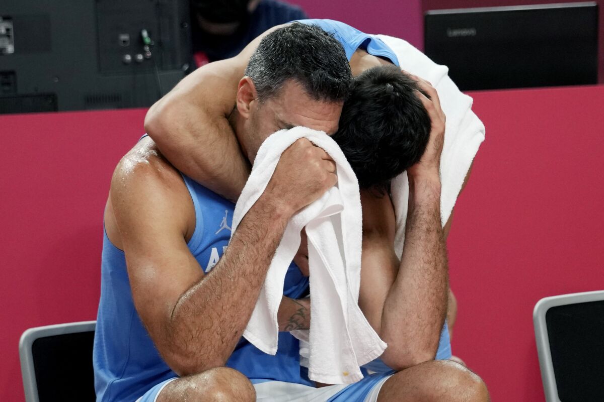 Argentina's Luis Scola (4) is hugged by teammate Facundo Campazzo as he receives an emotional standing 