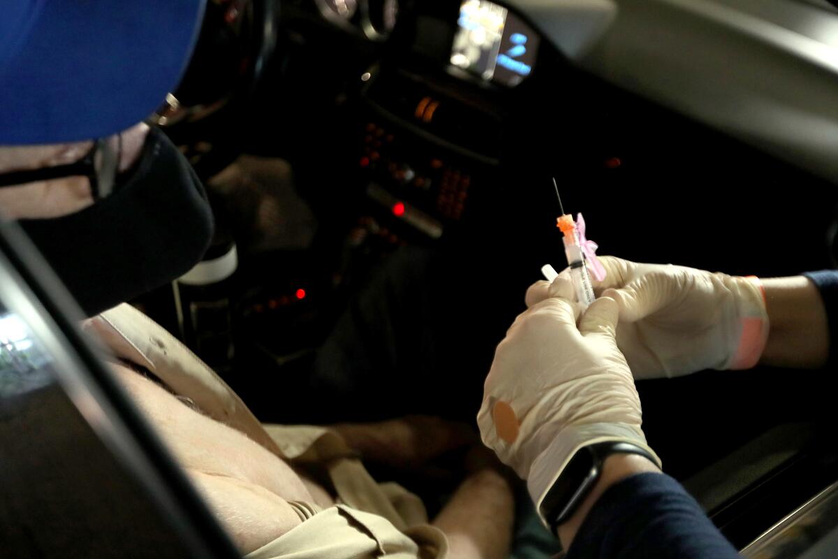 A person in a car prepares to receive a COVID-19 shot