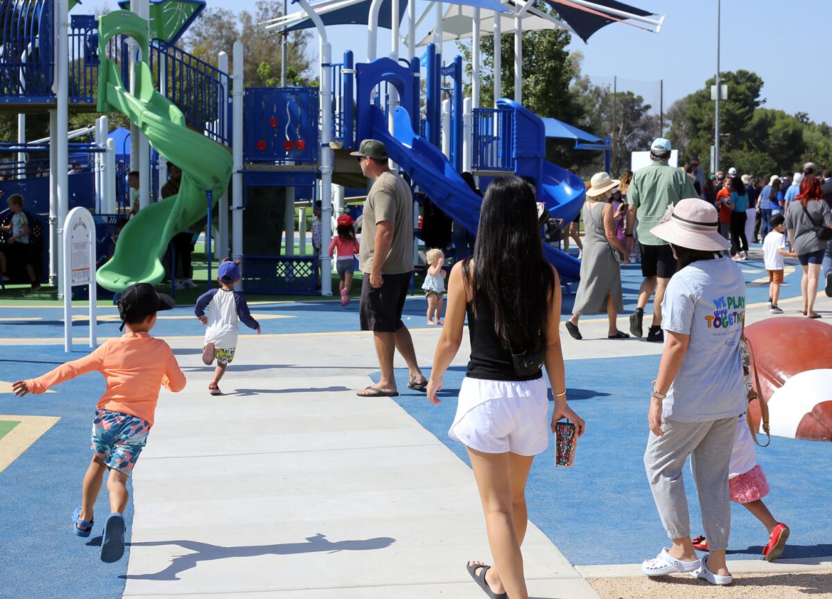 Families bring their children to play on the universally accessible playground at Fountain Valley Sports Park.