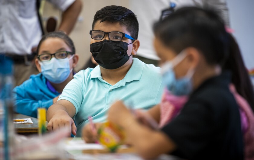 Mask-wearing third-graders in an elementary school classroom.