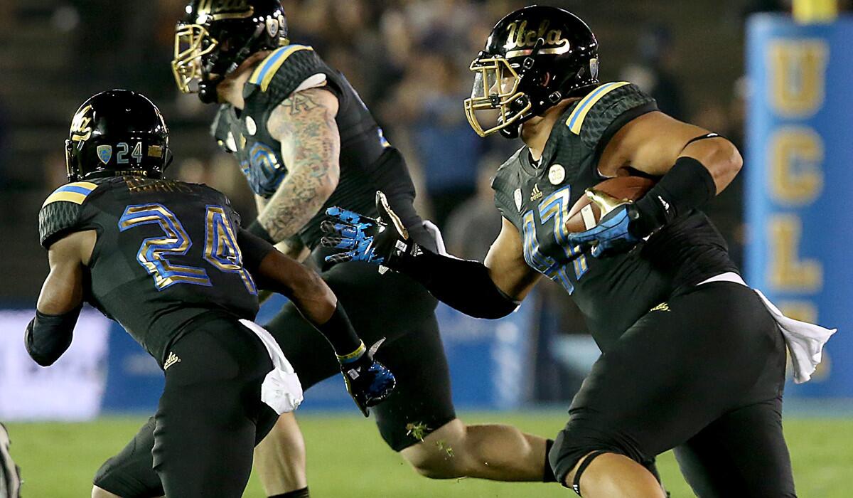 UCLA defensive end Eddie Vanderdoes returns a fumble during a game against Washington last season.