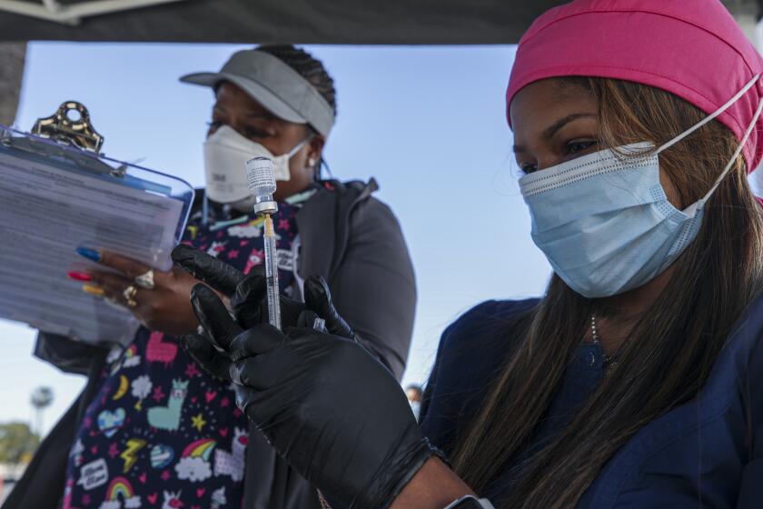 Ontario, CA - February 24: Out of state nurses Reshicka Upshaw, left, and Deanna Howard working at Convention Center on Wednesday, Feb. 24, 2021 in Ontario, CA.(Irfan Khan / Los Angeles Times)