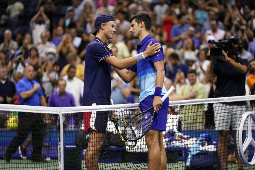 Holger Vitus Nodskov Rune of Denmark, left, and Novak Djokovic, of Serbia, meet at the net after Djokovic won their first-round match at the US Open tennis championships, Tuesday, Aug. 31, 2021, in New York. (AP Photo/Frank Franklin II)