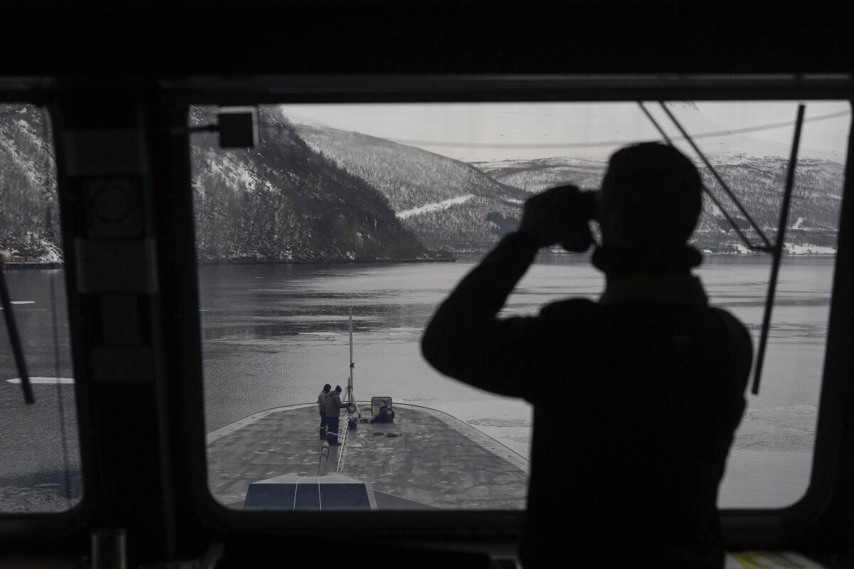 A man on a ship looks through binoculars