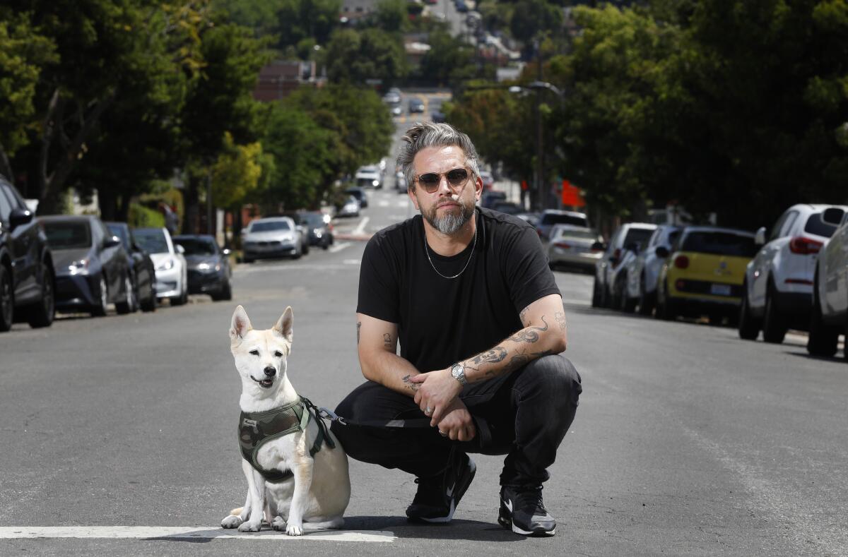 Richie Kulchar kneels in the street with his dog Molly.