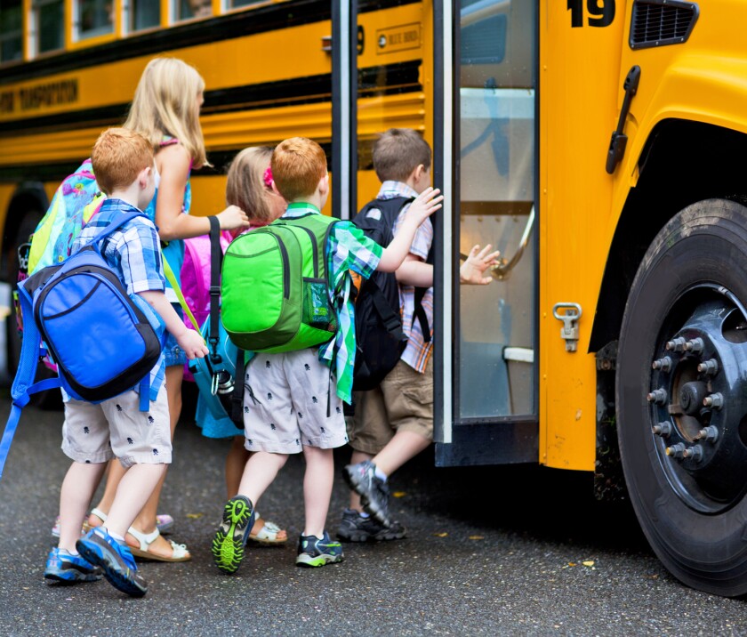 A group of young children getting on the schoolbus.