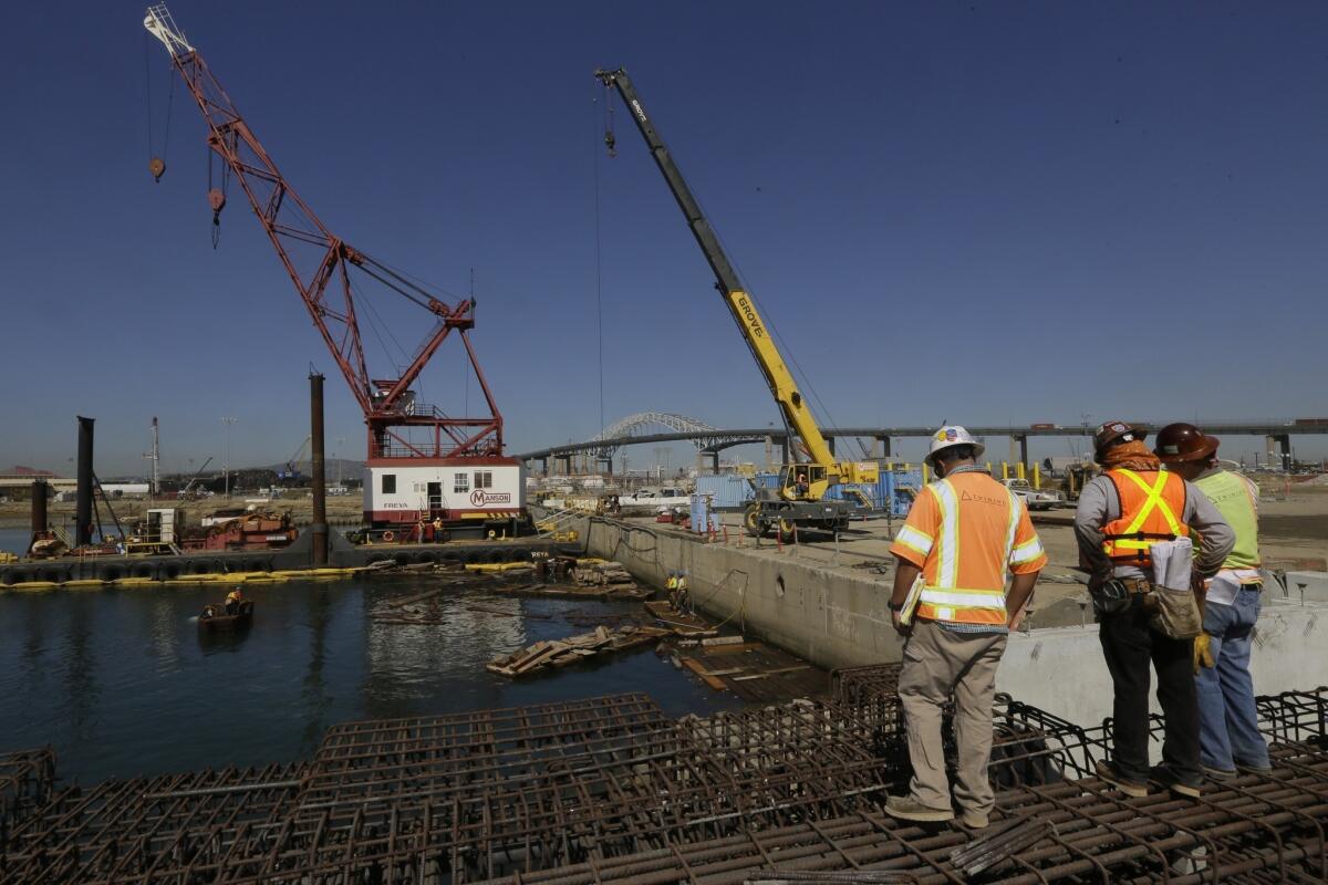 Construction workers expand the docks at the Port of Long Beach last year. An audit found that the city paid tens of thousands of dollars subsidizing the travel costs of harbor officials' spouses, despite city restrictions banning such spending.