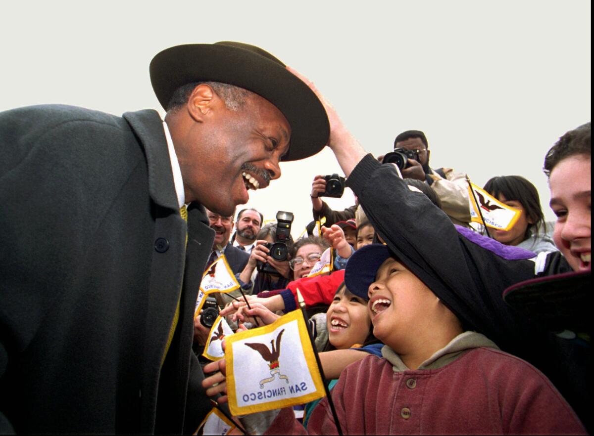 A child reaches out to touch Willie Brown.
