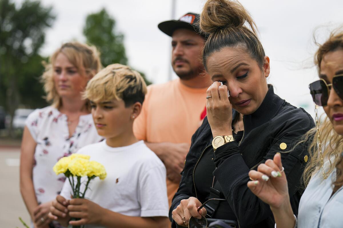 A woman wipes away a tear at a memorial.