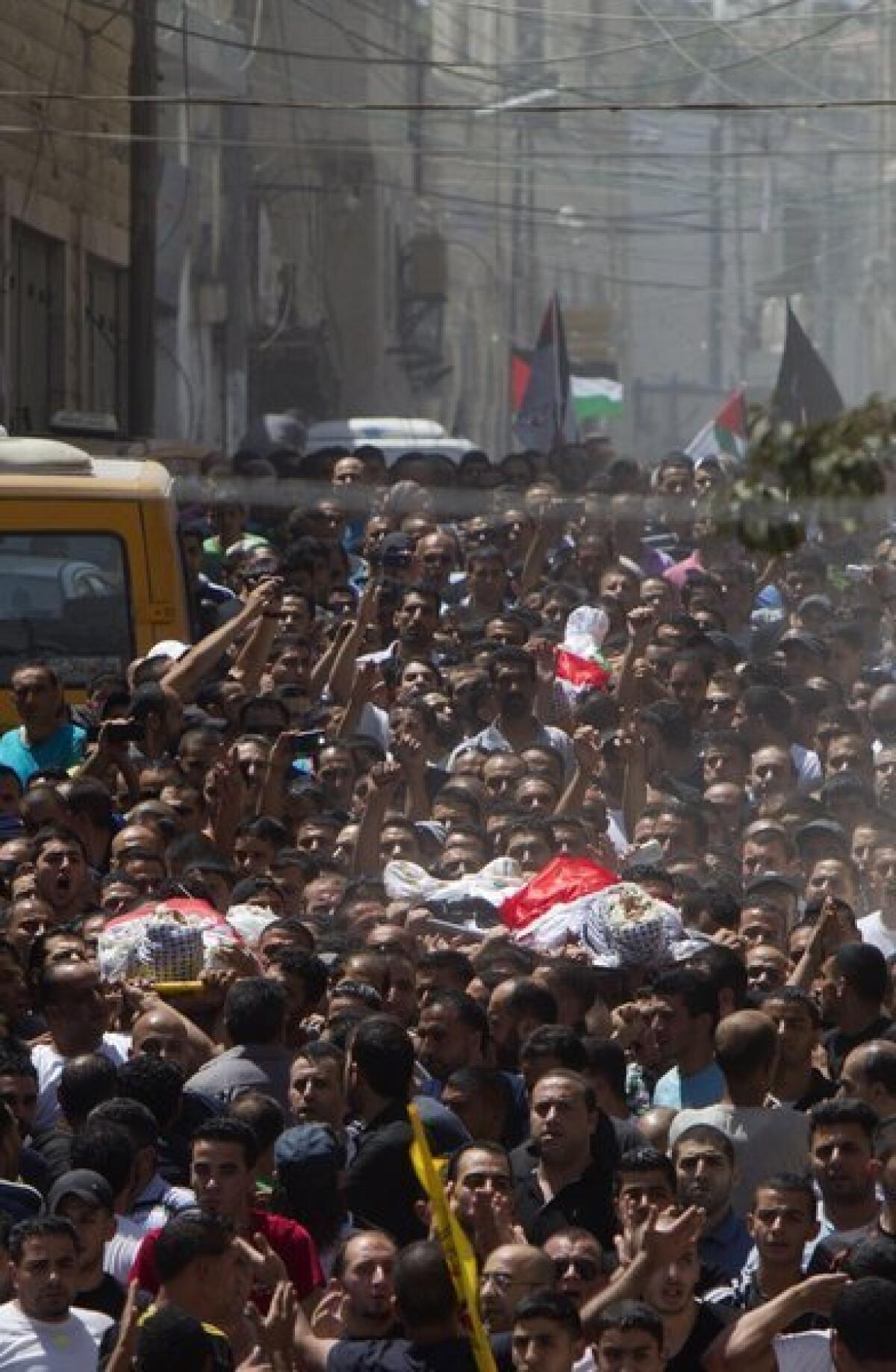 Palestinian mourners carry the bodies of three men who were killed during clashes with Israeli security forces in the West Bank's Kalandia refugee camp on Monday.