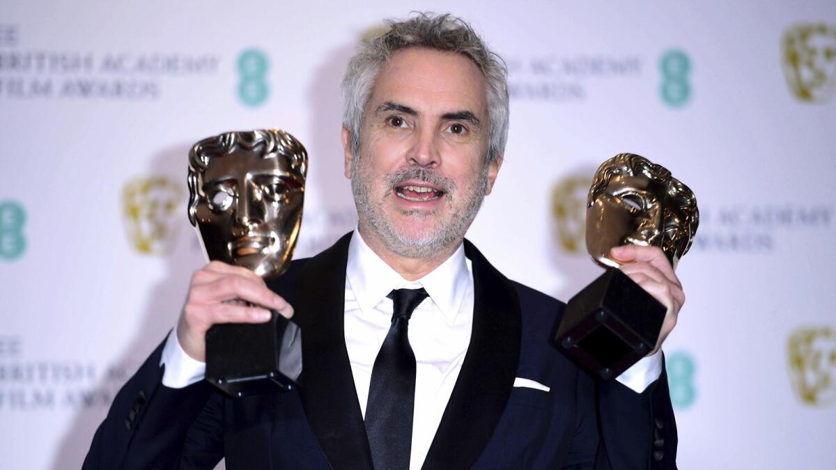 Alfonso Cuarón with his best film and director awards poses in the press room at the 72nd British Academy Film Awards at the Grosvenor House Hotel in London on Sunday, Feb. 10, 2019.