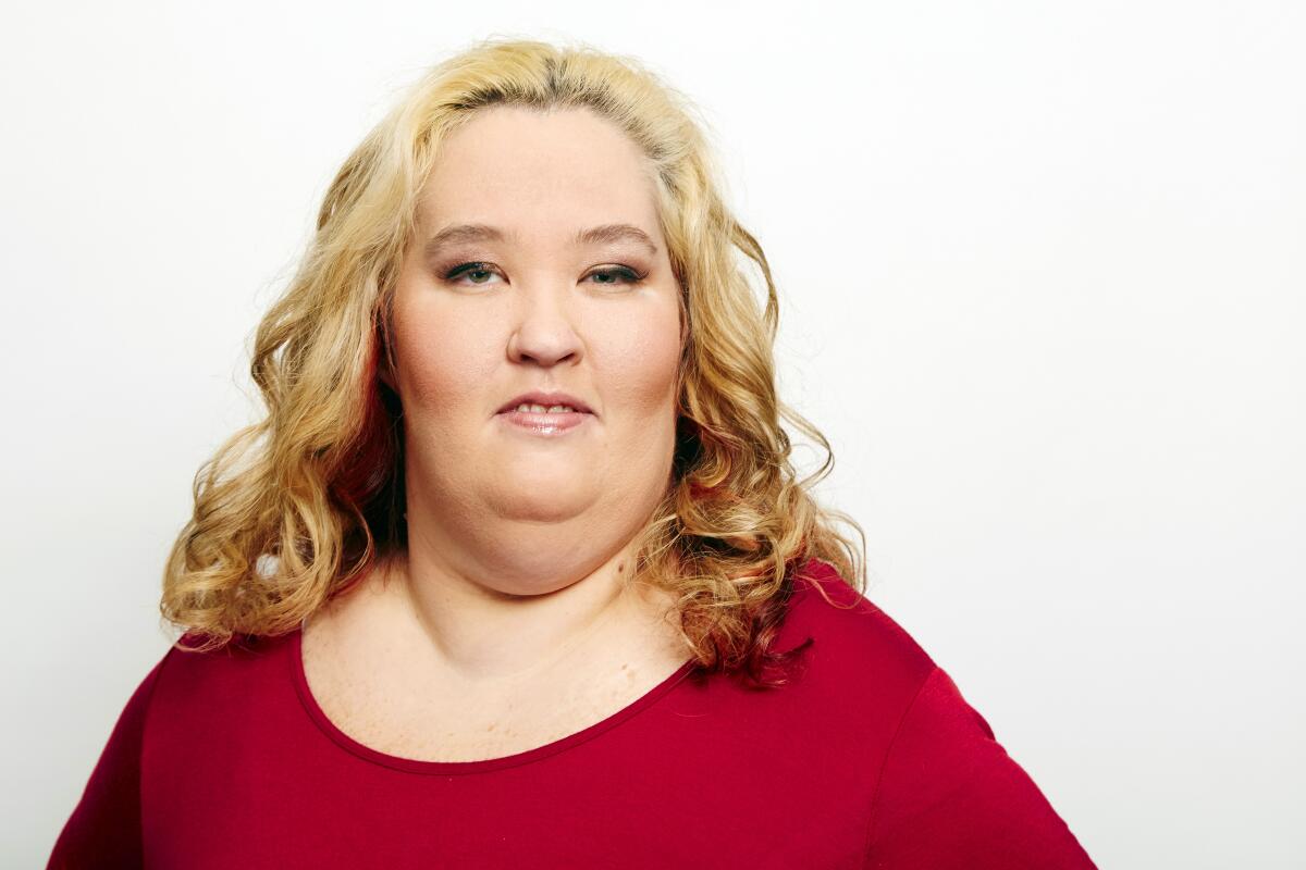 June Shannon, better known as Mama June, poses for a portrait wearing a red blouse and blond curly hair.