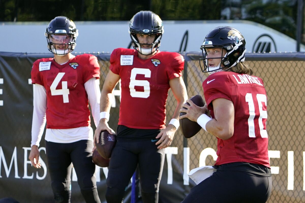 Jacksonville Jaguars quarterback Trevor Lawrence (16) runs through a drill as quarterback's Kyle Sloter (4) and Jake Luton (6) look on during an NFL football practice, Sunday, July 31, 2022, in Jacksonville, Fla. (AP Photo/John Raoux)